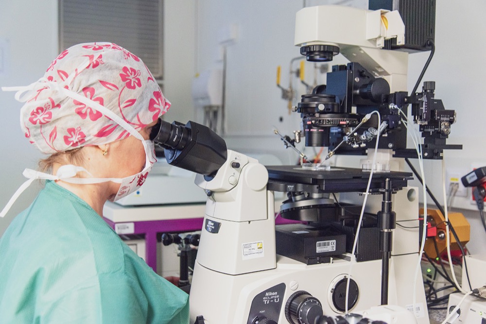 Embryoložka u mikroskopu v embryologické laboratoři
