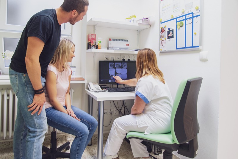 Lékařka ukazuje páru výsledky ultrazvukového vyšetření na monitoru